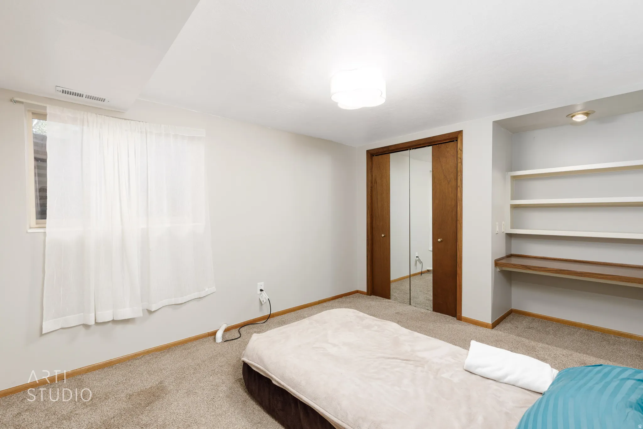 Built-in shelving with desk space, mirrored closet doors, and neutral carpeting