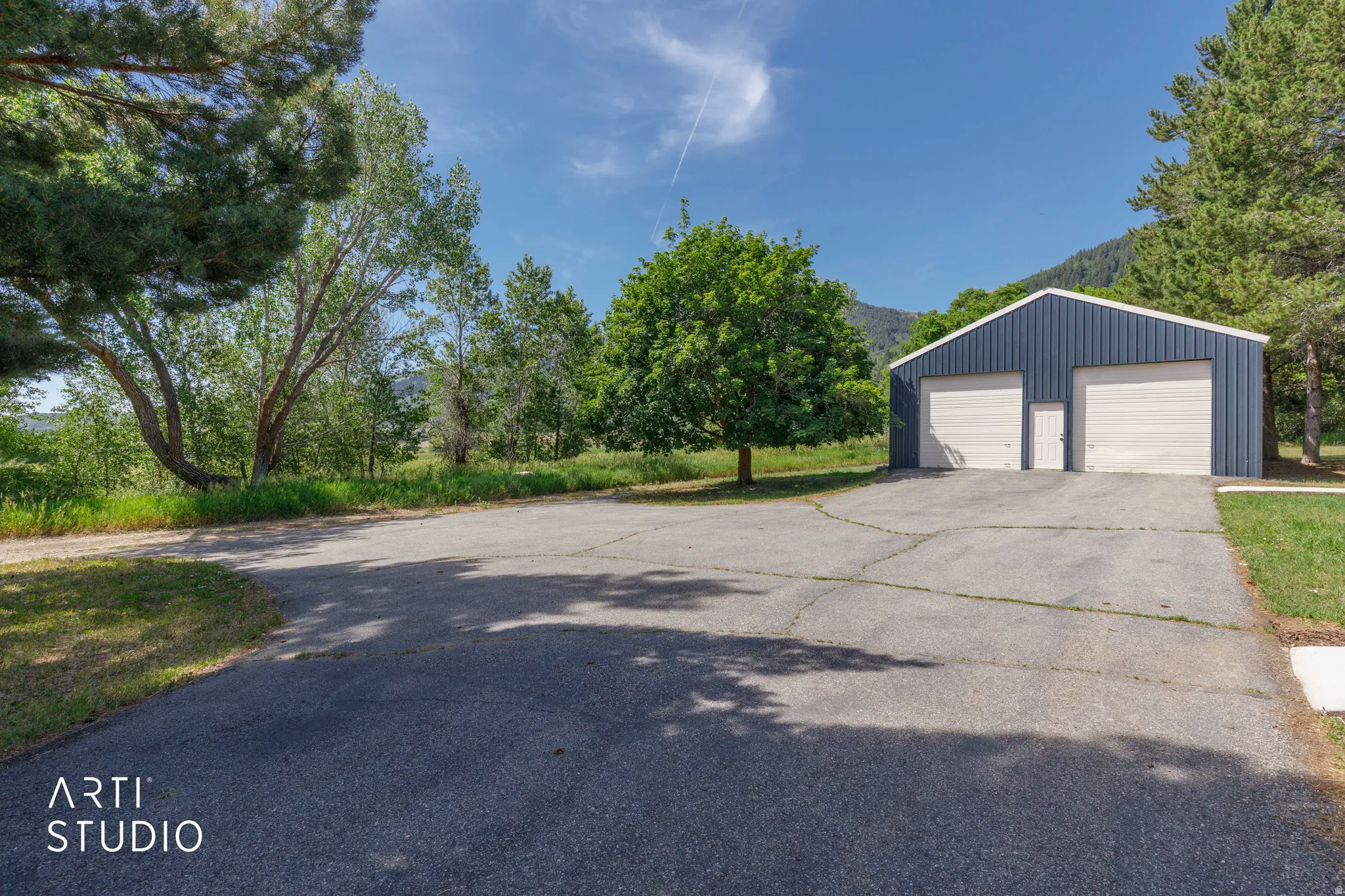 Blue metal-sided outbuilding with two garage doors and a service door