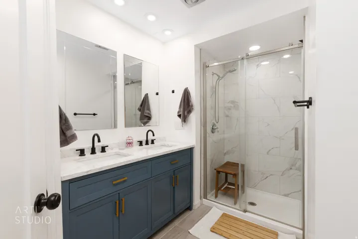 Dual vanity with dark blue cabinetry, matte black fixtures, and a light-colored countertop