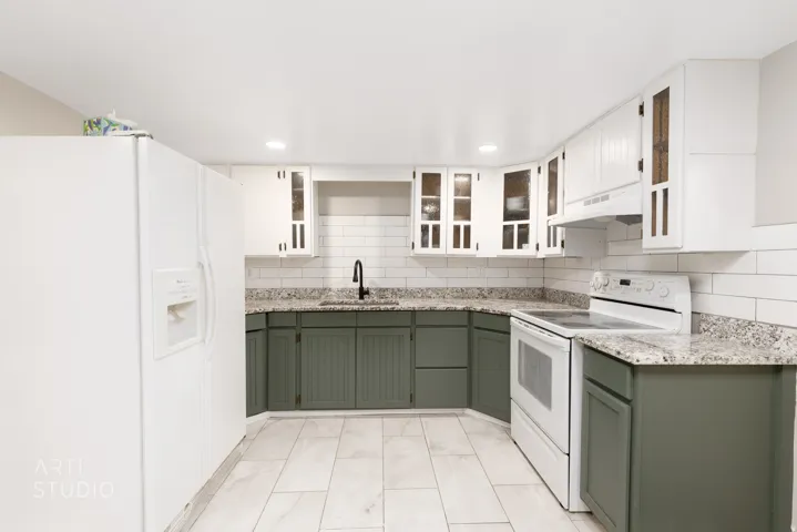 Kitchen featuring white tile flooring, lower cabinetry, upper cabinetry, stone countertops, and a subway tile backsplash