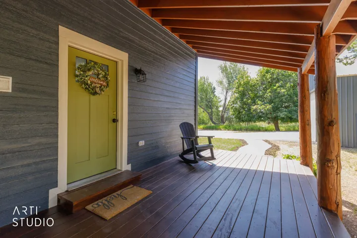 Covered front porch with wood-finish flooring, natural wood posts, and a wood-slat ceiling