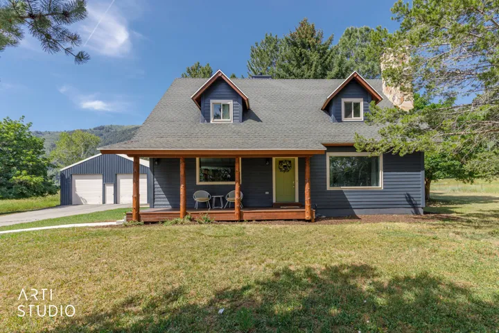 Siding exterior with dormer windows, covered front porch with wood-finish columns, and a two-car detached garage with a separate entry