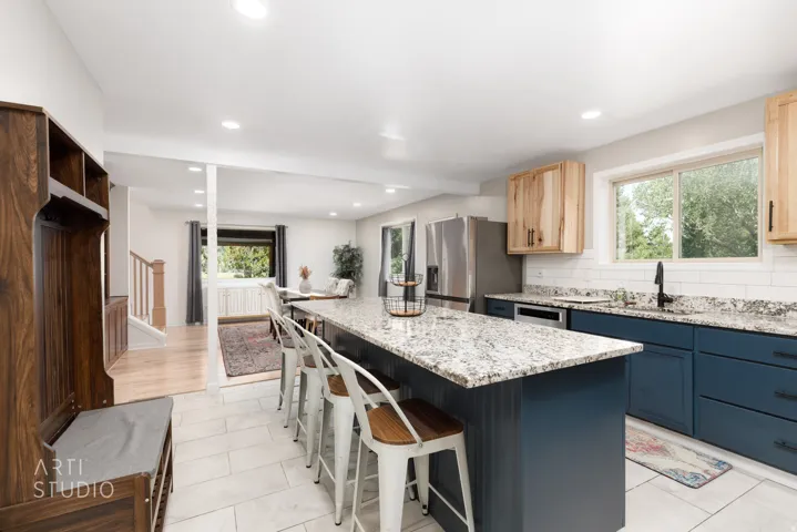 Kitchen featuring a large central island, granite countertops, stainless steel appliances, and wood-finish cabinetry