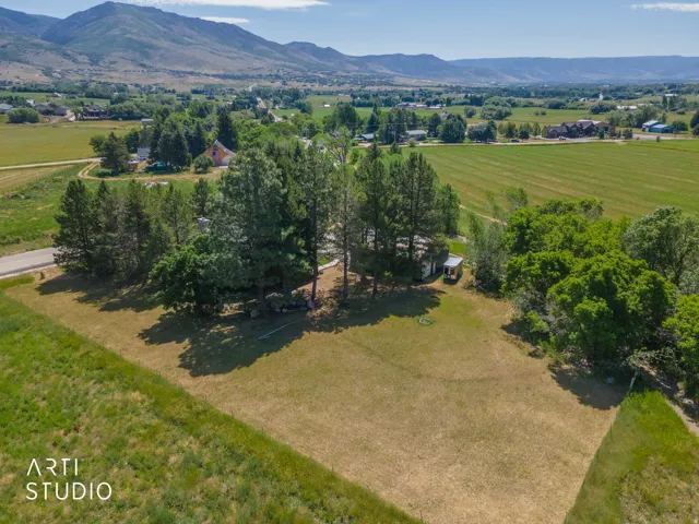 Expansive property with mature trees, green fields, and distant mountains