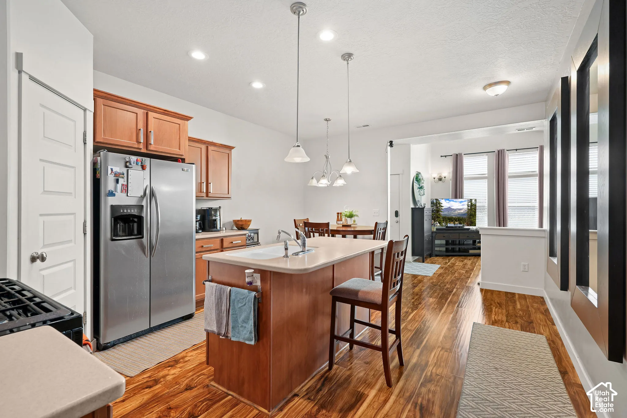 Kitchen featuring wood-finish flooring, recessed lighting, and a kitchen island with integrated sink