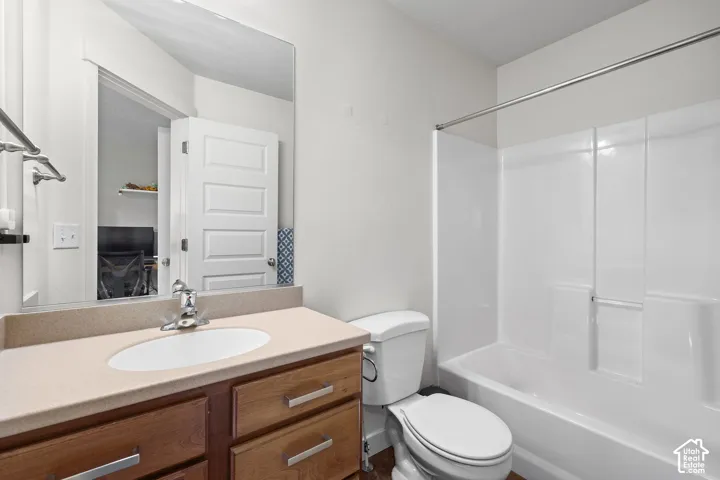 Bathroom featuring a light-toned countertop, wood-finish vanity with drawer pulls, integrated sink, chrome faucet, and a combination shower and tub with a white surround