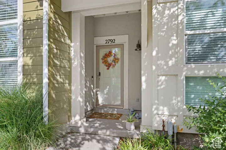 Recessed entry with a white door, exterior wall sconce, and concrete porch