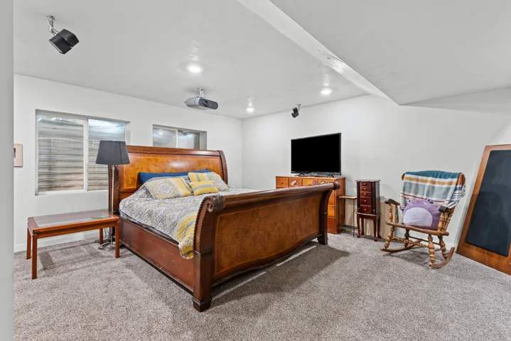 Recessed ceiling lighting, ceiling-mounted projector, wall-mounted speakers, two windows with blinds, and carpeting
