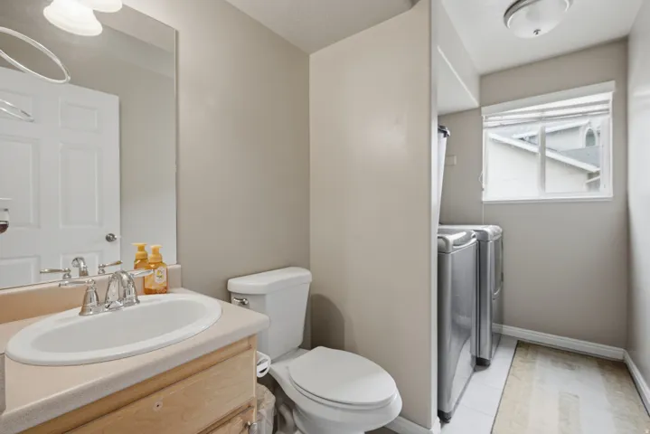Vanity with an integrated sink and chrome faucet, white toilet, and tile flooring