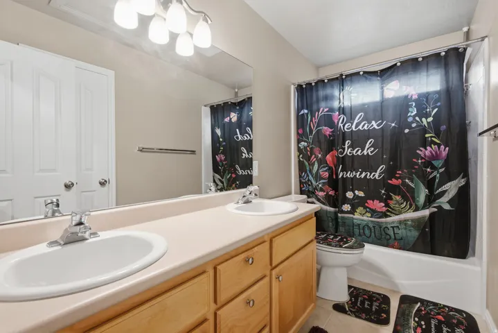 Double vanity with two undermount sinks, light wood-finish cabinetry, and a large wall-mounted mirror