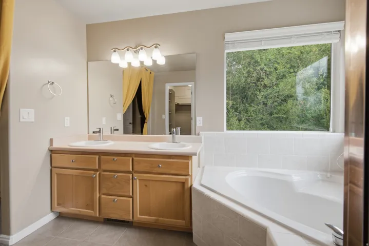 Dual vanity with undermount sinks, neutral countertop, and wood-finish cabinetry