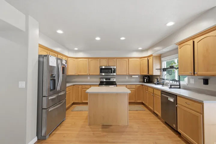 Kitchen featuring wood-finish flooring, recessed lighting, a central island, and wood cabinetry with a light countertop