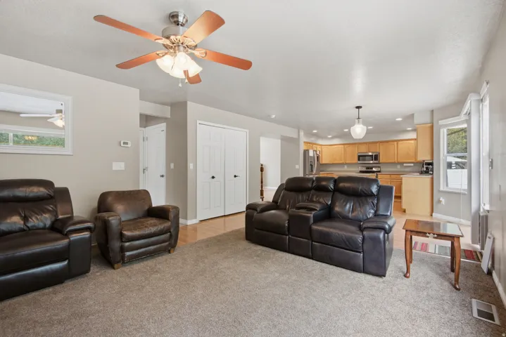 Open-concept living area featuring a ceiling fan, recessed lighting, and a kitchen with wood-finish cabinetry, stainless steel appliances, and a window