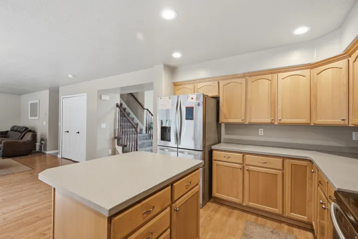 Kitchen featuring light wood cabinetry, light-toned countertops, stainless steel refrigerator, and recessed lighting