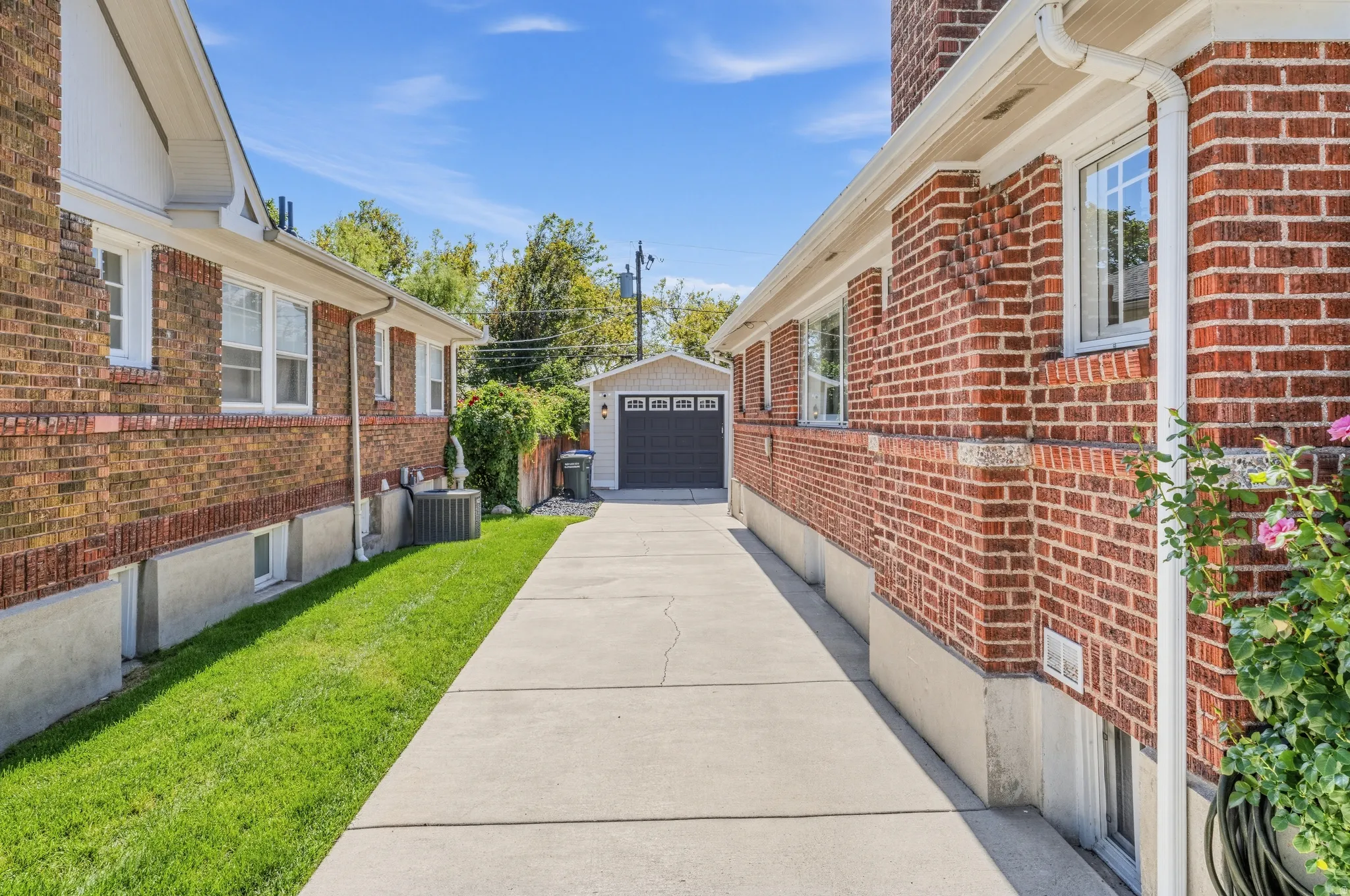 Concrete driveway providing access to a detached garage with a dark panel door