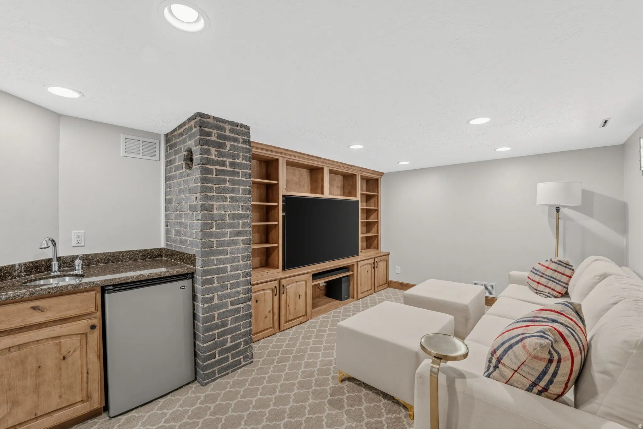 Recessed lighting illuminates a built-in entertainment center with open shelving and lower cabinetry