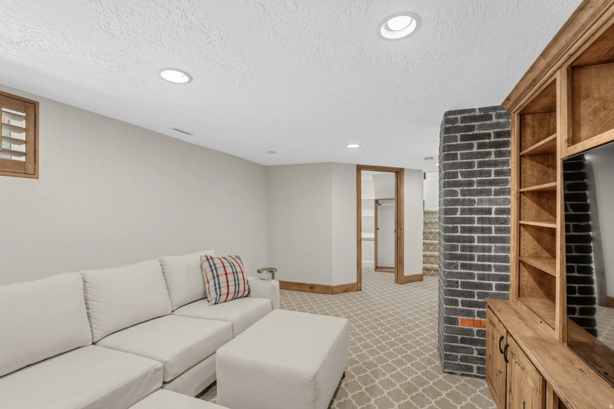 Recessed lighting illuminates this space featuring a textured ceiling and a window with wood-finish shutters