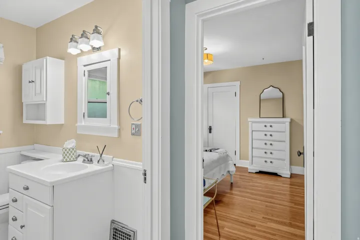 Bathroom featuring a white vanity with integrated sink, white shaker-style wall cabinet, and a framed mirror