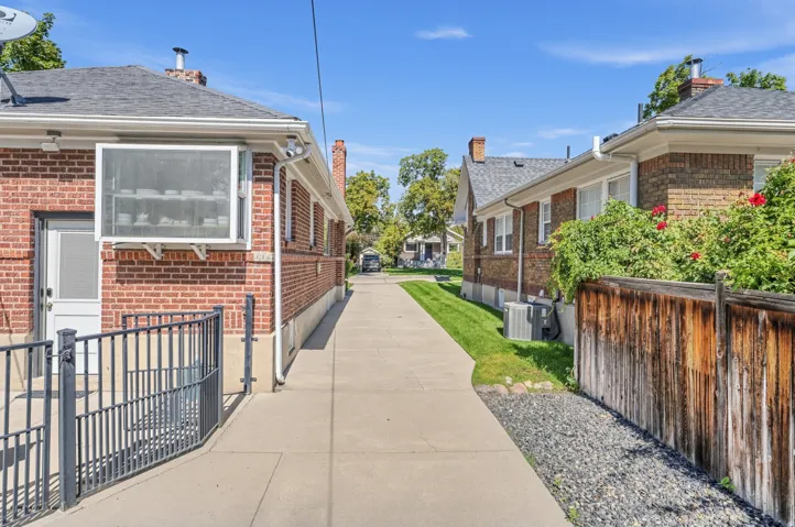 Brick exterior, gabled roofline, concrete driveway, wood privacy fence, and integrated window unit