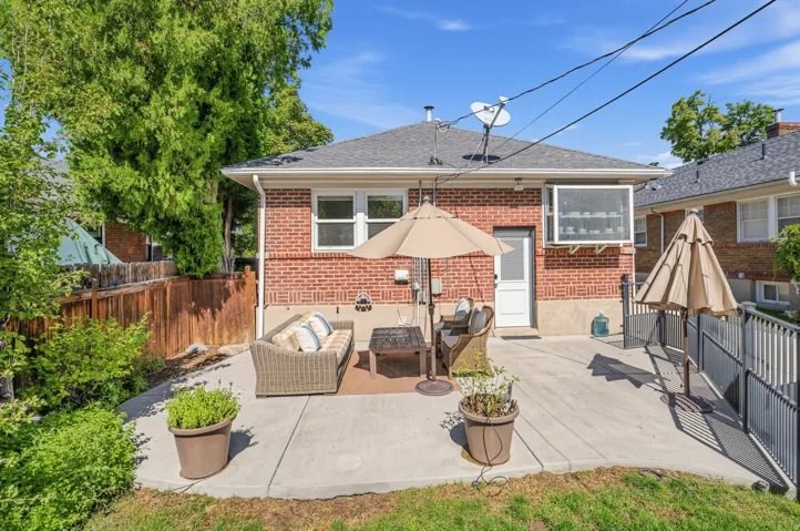 Concrete patio with red brick exterior, white framed windows, and a wood privacy fence