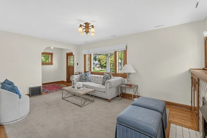 Hardwood flooring, arched doorway, wood-frame windows, and a built-in fireplace with white tile surround