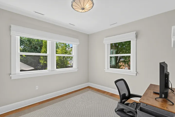 Bright room featuring two large windows, wood-finish flooring, and a semi-flush mount ceiling light