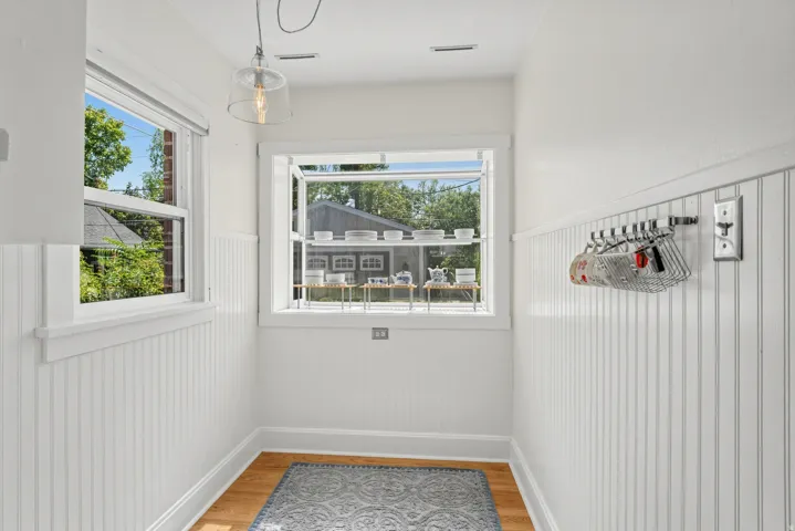 Two windows providing natural light, white beadboard wainscoting, wood-finish flooring, and an overhead pendant light fixture