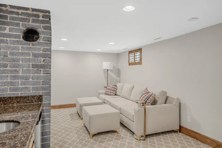 Built-in wet bar with a speckled countertop and undermount sink, brick-finish accent wall, recessed lighting, and patterned carpeting