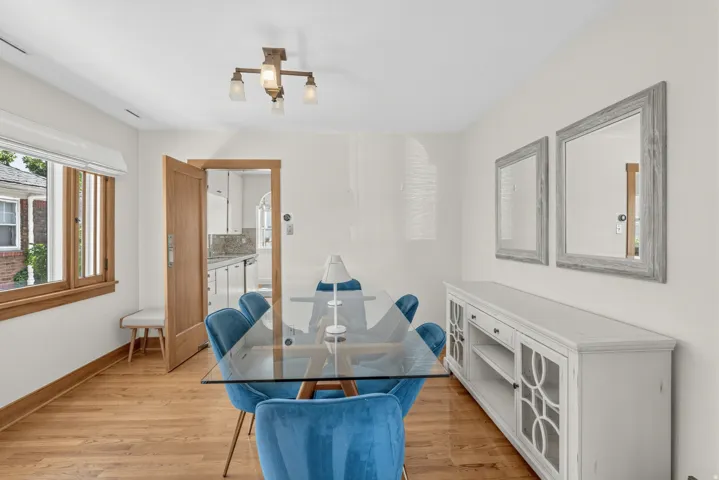 Hardwood flooring, wood-framed windows, and a multi-light ceiling fixture enhance this bright interior