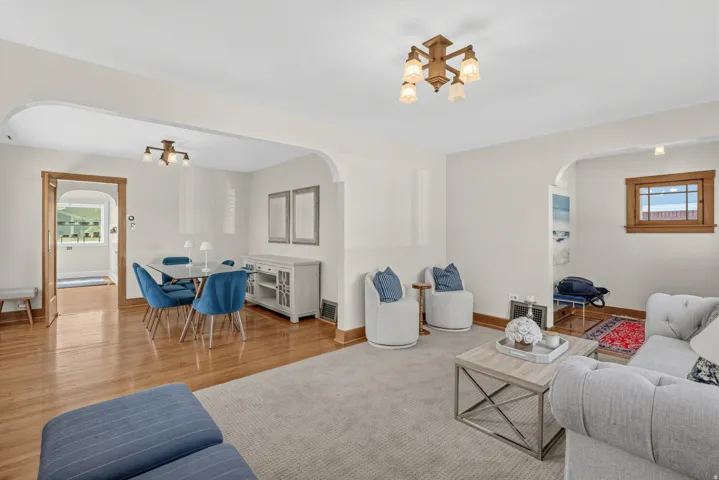 Hardwood flooring, arched doorways, recessed lighting, wood-trimmed windows, and a built-in buffet with glass-front cabinetry