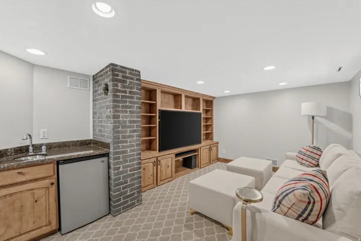 Recessed lighting illuminates a built-in entertainment center with open shelving and lower cabinetry