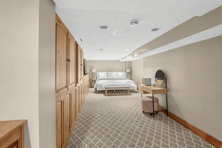 Wall-to-wall wood-finish cabinetry, patterned carpet flooring, recessed lighting, and wood trim detailing