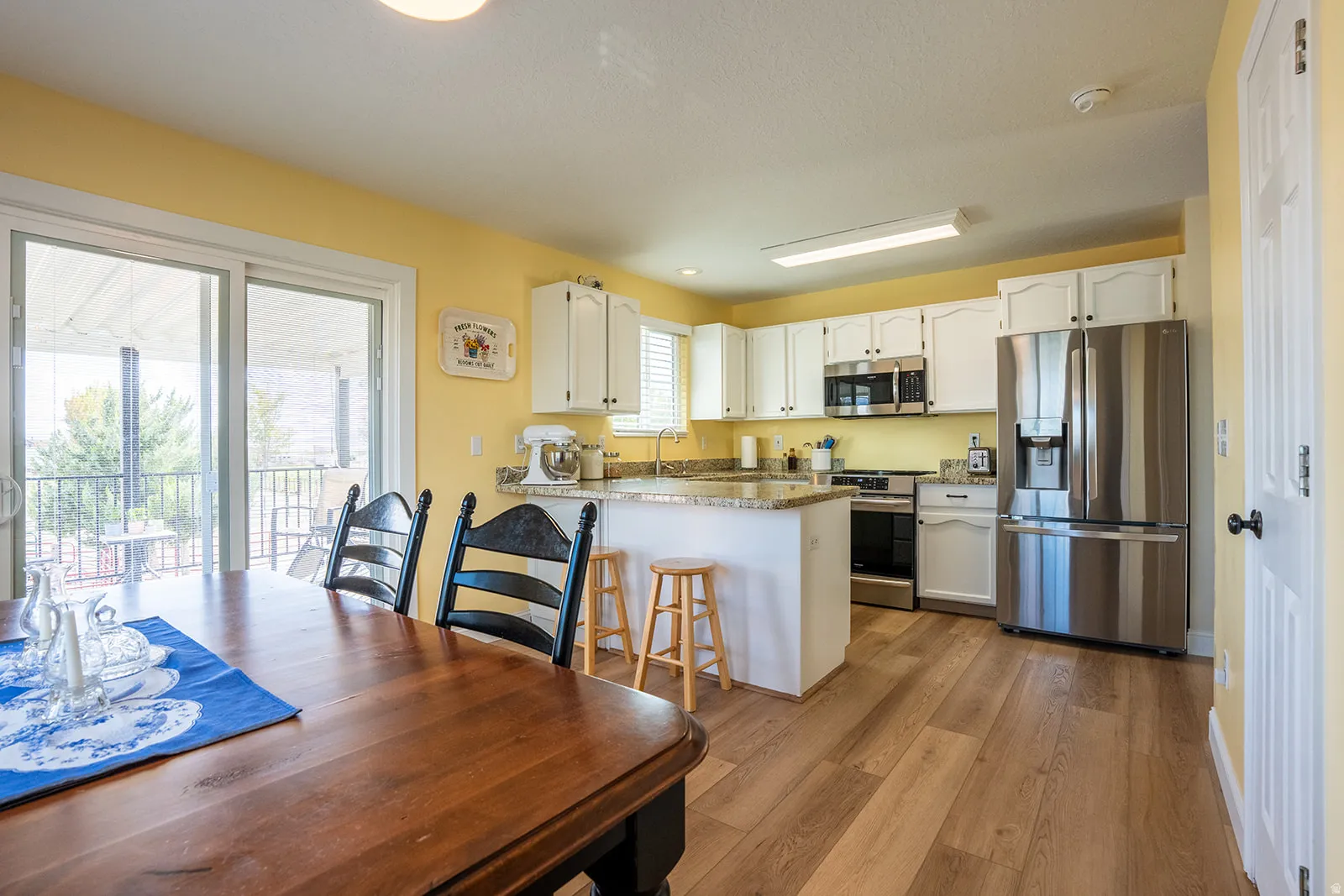 Kitchen with wood-finish flooring, white cabinetry, stainless steel appliances, and light-toned countertops