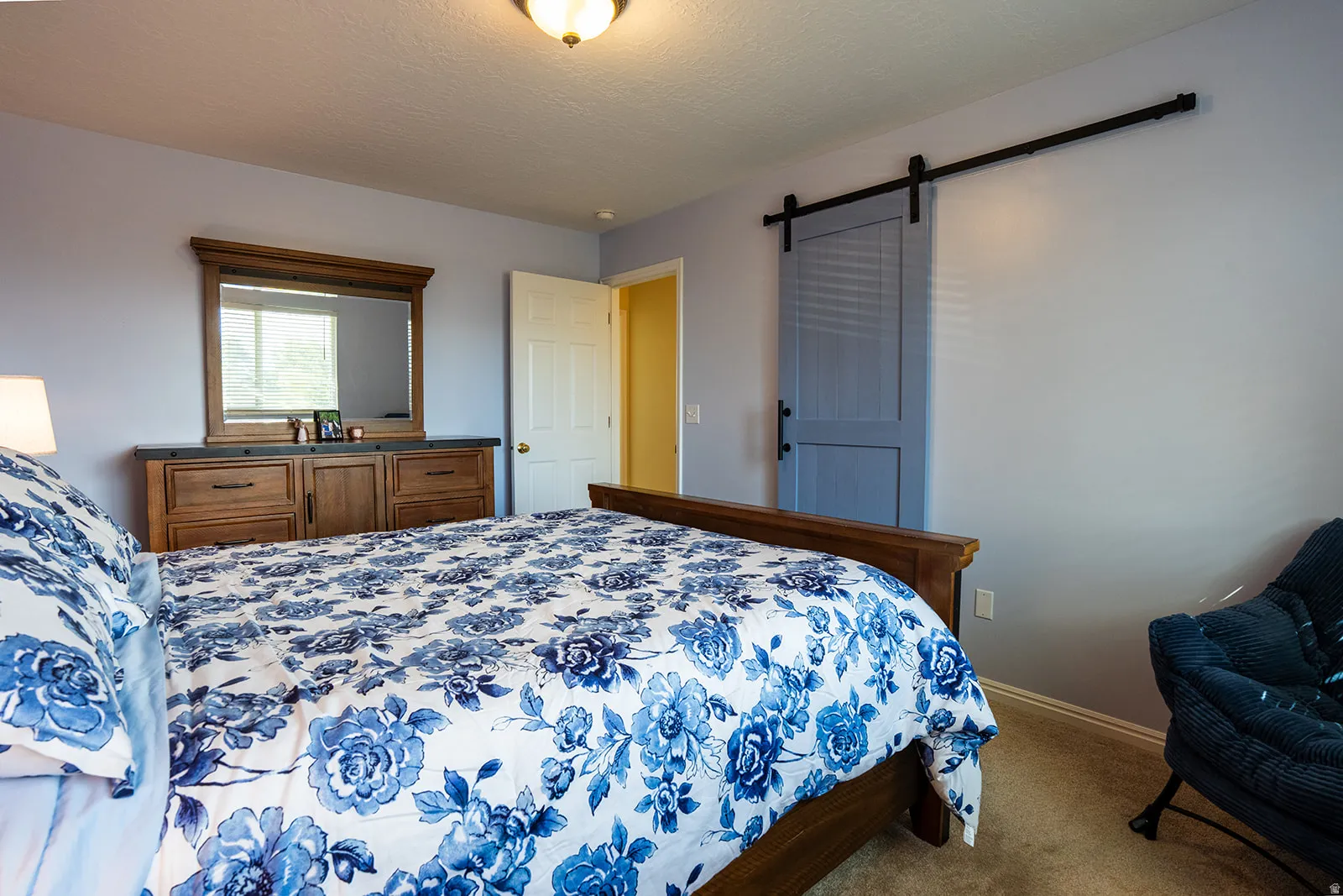Spacious room featuring a sliding barn door, wood-finish flooring, and a ceiling-mounted light fixture
