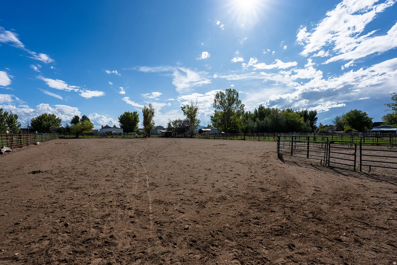 Expansive outdoor arena featuring a dirt surface and perimeter fencing with gate