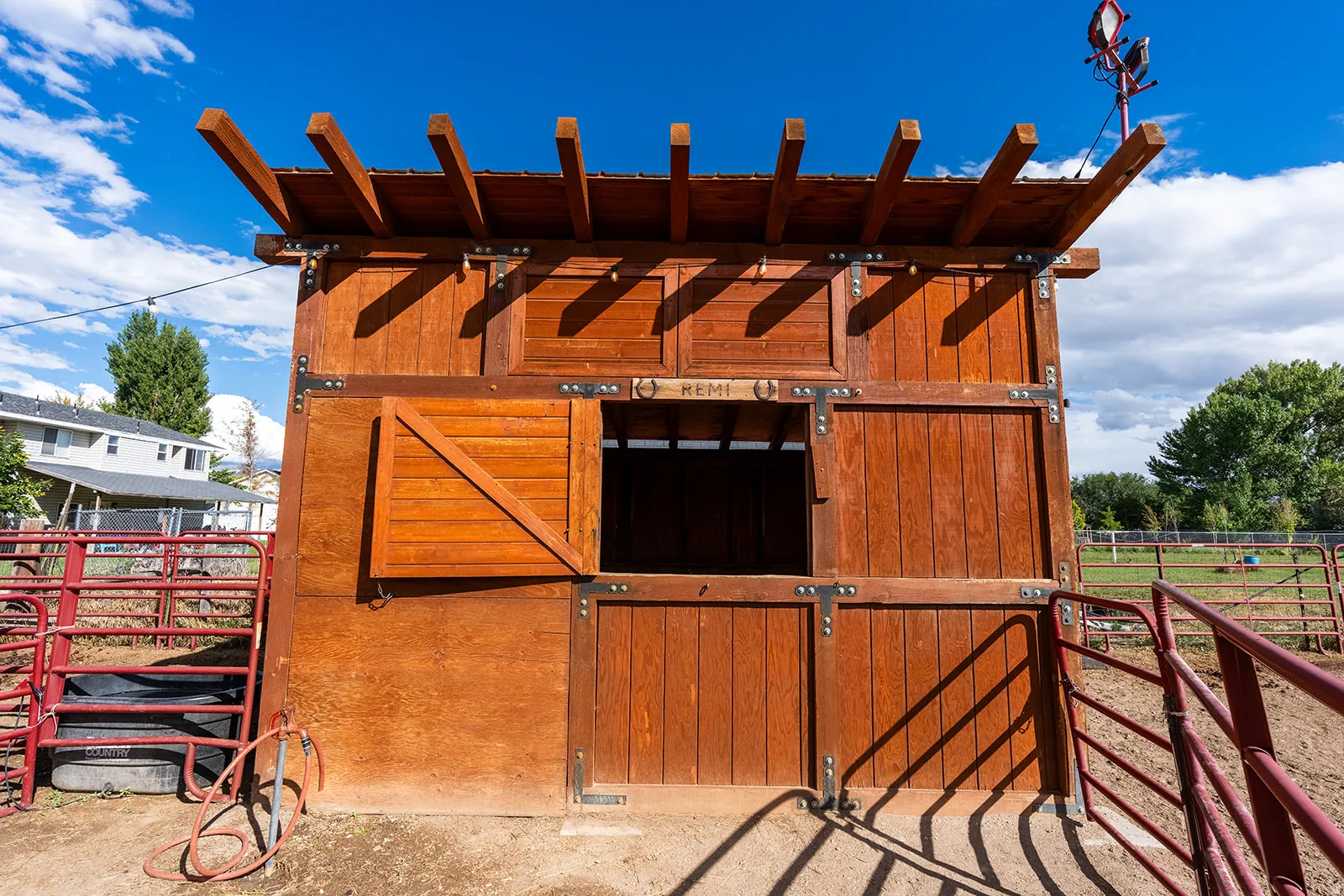 Wood-clad outbuilding featuring a slatted overhang and an open window with a swinging shutter