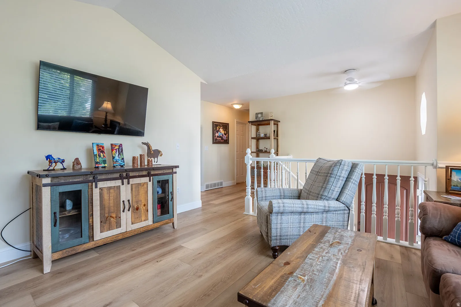 Wood-finish flooring, vaulted ceilings, and a built-in media console with cabinet storage