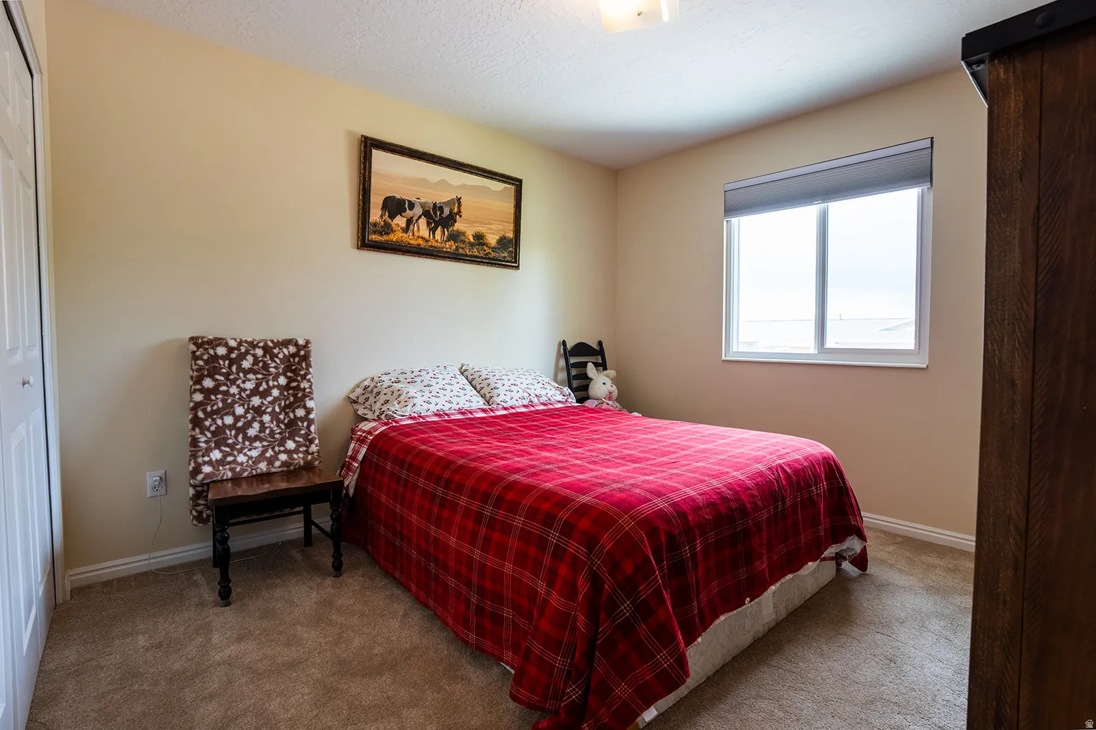 Neutral tone wall paint, carpeted flooring, and a white framed window