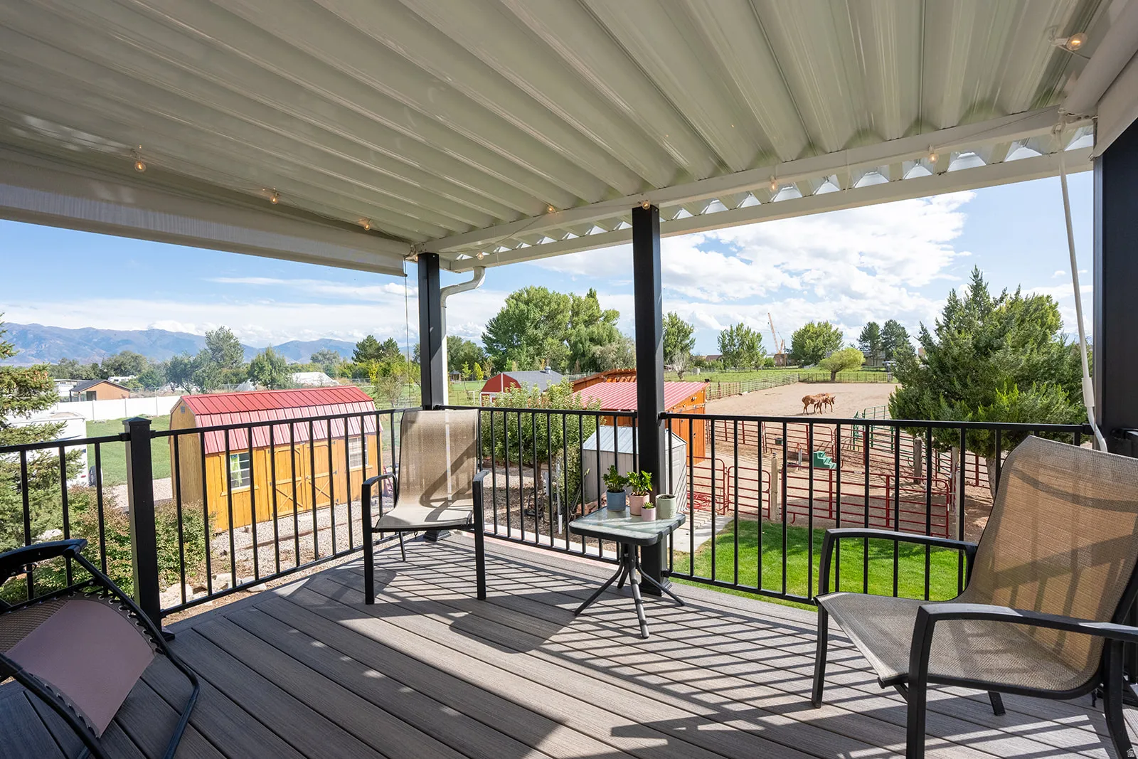 Covered deck with composite decking, black metal railings, and a distant mountain backdrop
