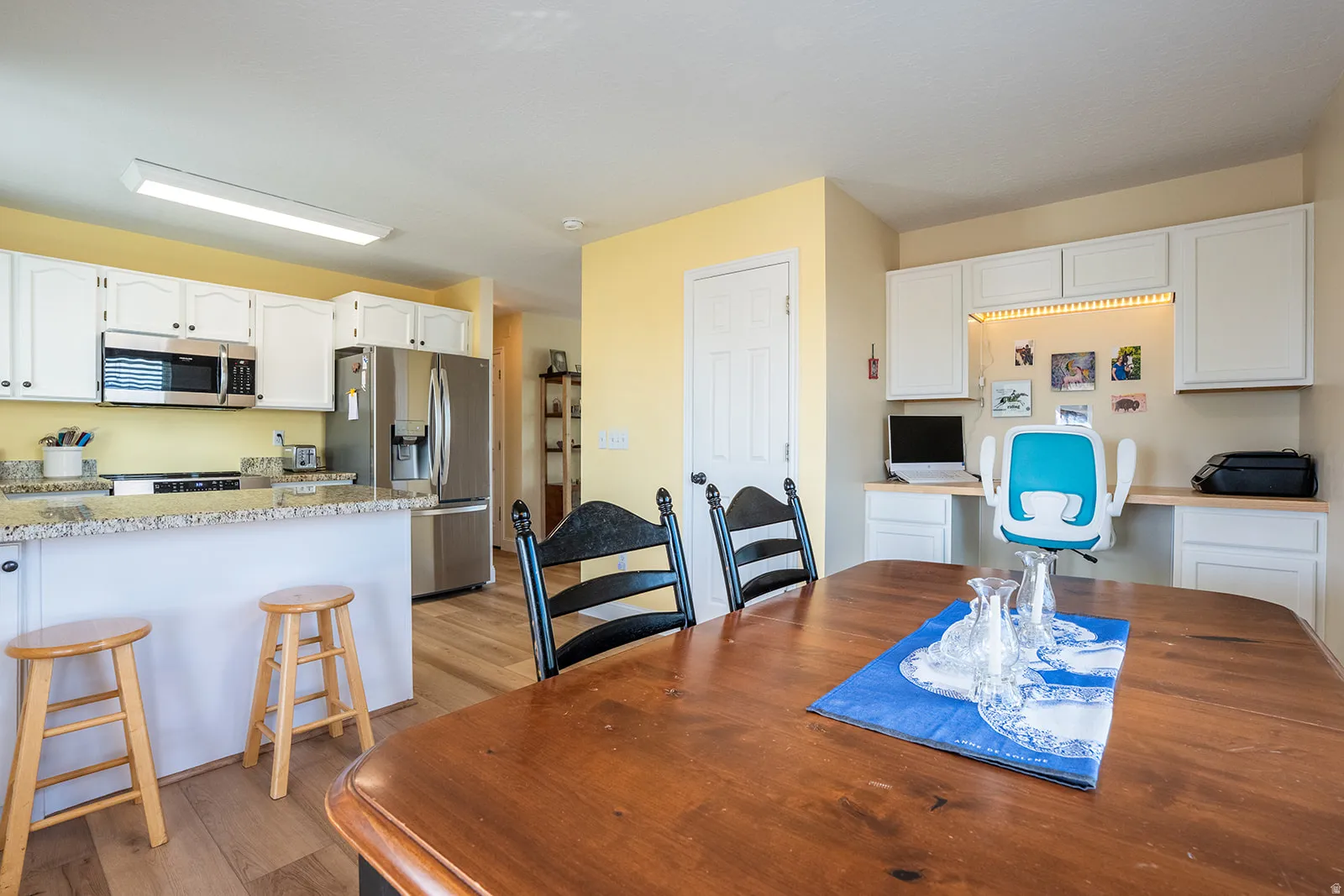 Kitchen featuring white cabinetry, stainless steel appliances, and wood-finish flooring