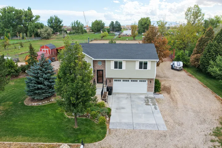 Two-story residence with a two-car garage, brick and siding exterior, concrete driveway, and gravel parking area