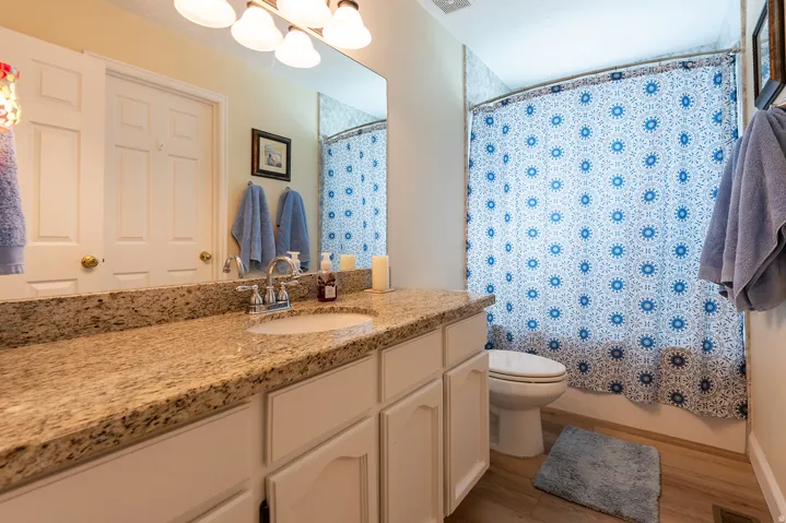 Granite-finish countertop with an integrated sink, white cabinetry, and wood-finish flooring
