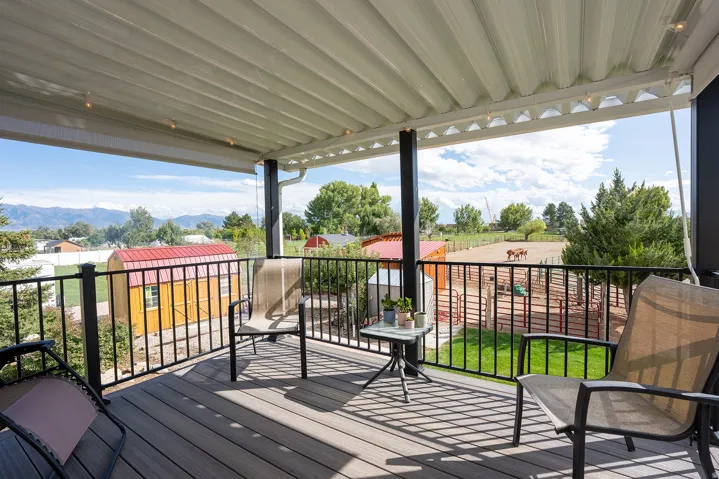 Covered deck with composite decking, black metal railings, and a distant mountain backdrop
