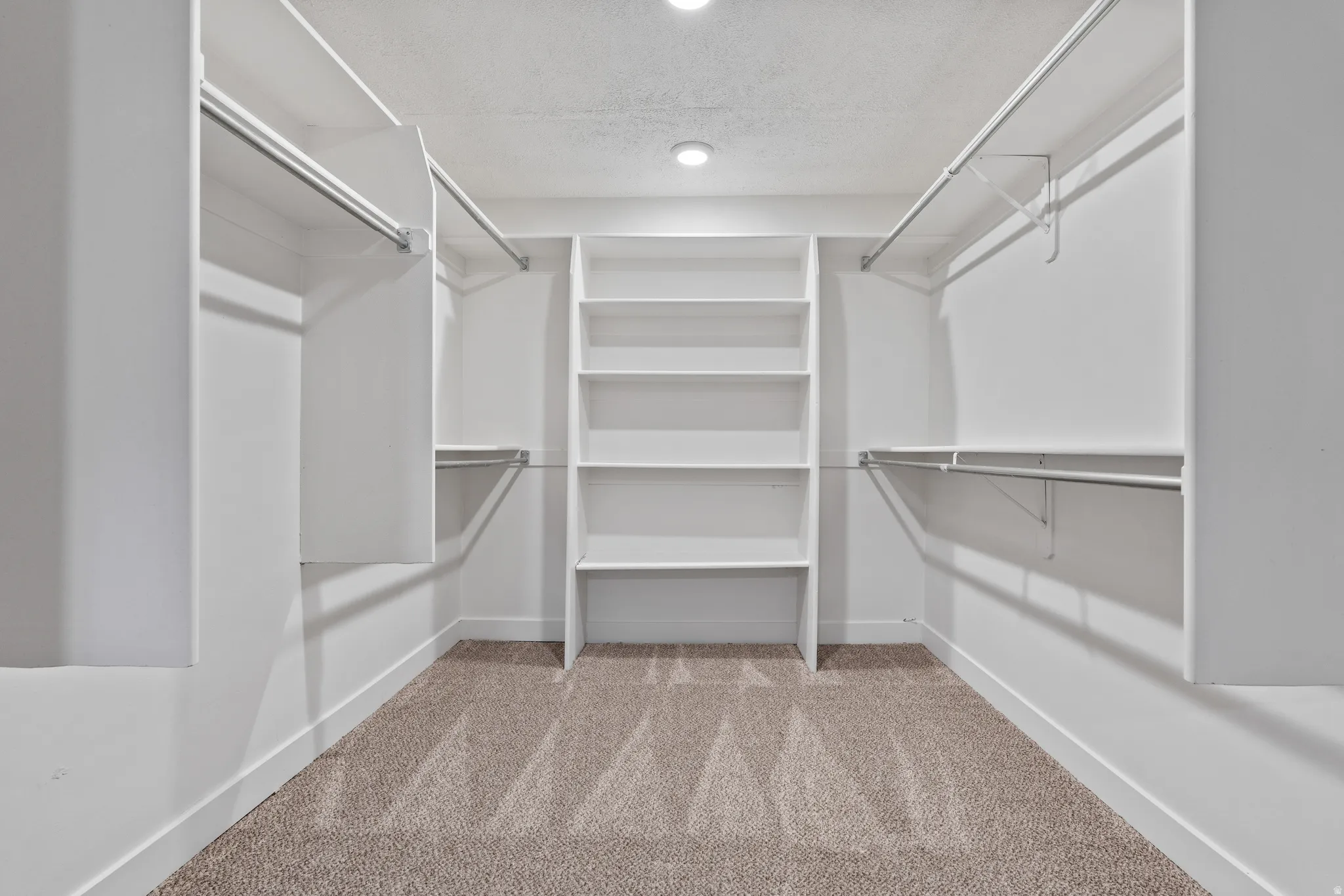 Built-in shelving, multiple hanging rods, recessed lighting, and carpet flooring