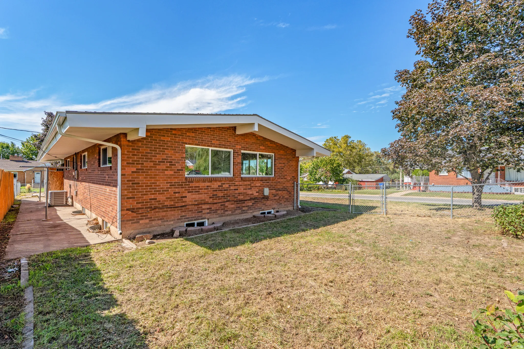 Brick exterior with a covered concrete walkway and a chain-link fence