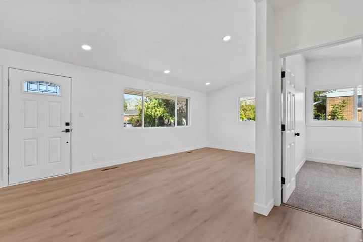 Recessed lighting, wood-finish flooring, white paneled door with decorative glass, white walls, and multiple windows