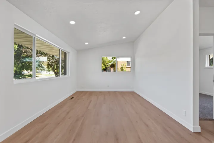 Spacious room featuring multiple windows, recessed ceiling lighting, and wood-finish flooring