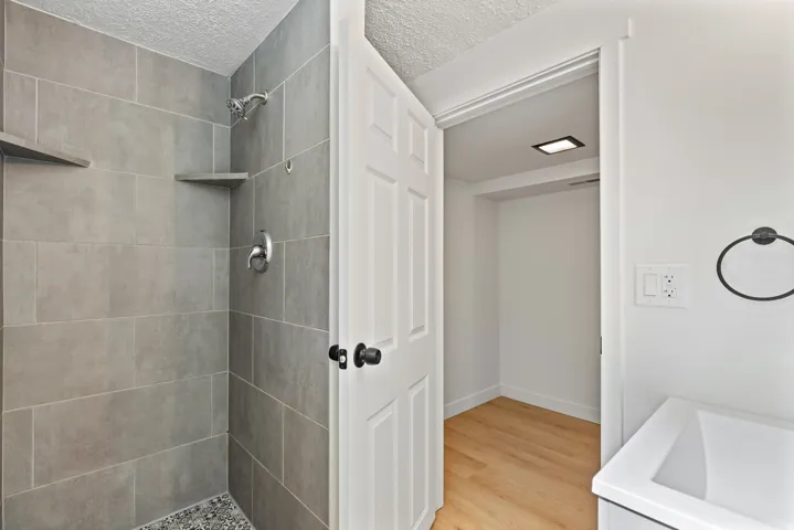Walk-in shower with gray tile surround and built-in shelving
