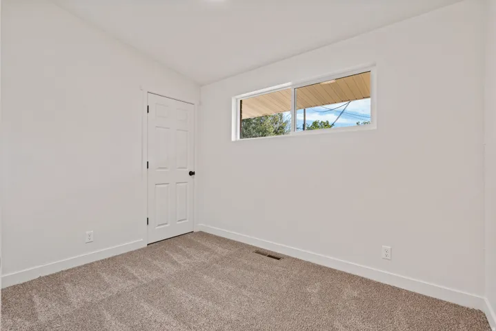 Neutral wall paint, plush carpet flooring, white trim, and a horizontal window