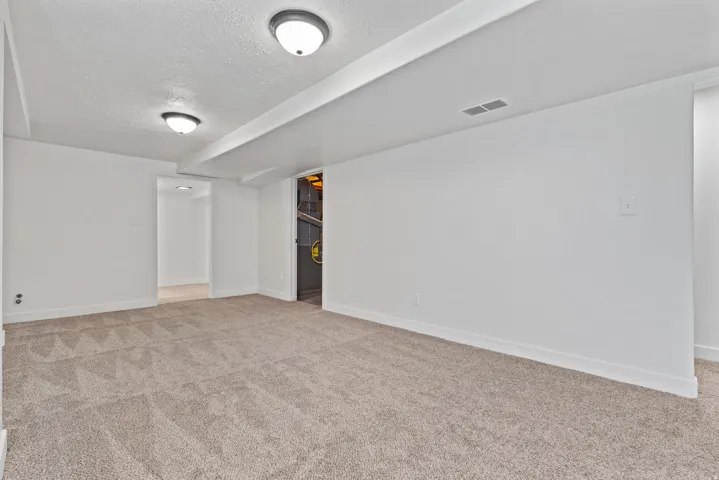 Expansive room with neutral carpeting, recessed lighting, and white walls